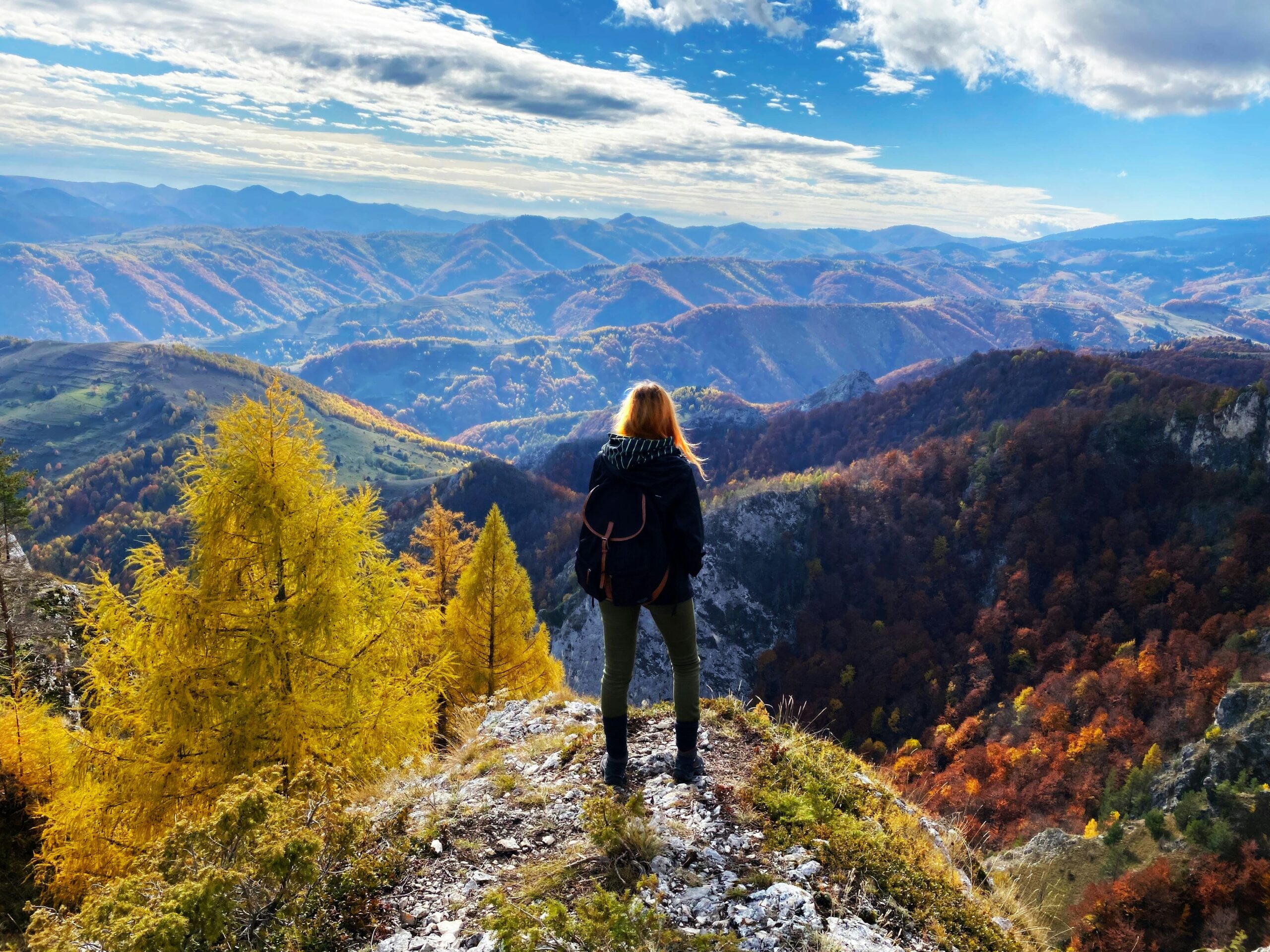 Frau am wandern, auf einem Hügel stehend sieht man sie von hinten