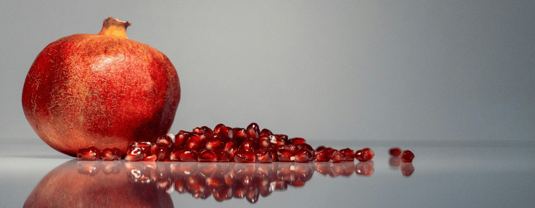Granatapfel als ganze Frucht und im Vordergrund kerne