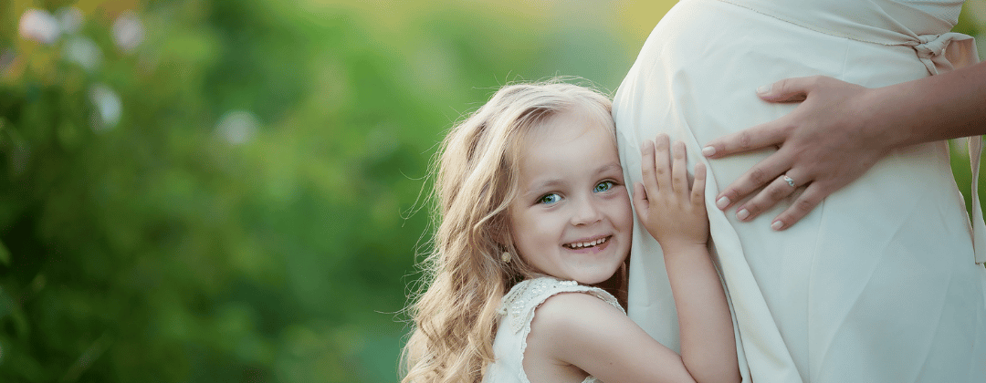 Folsäure in der Schwangerschaft: Blondes Mädchen umarmt schwangere Mama