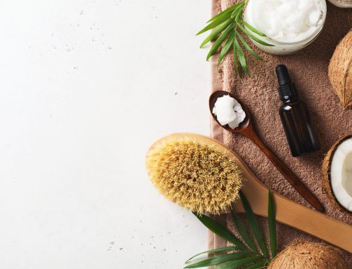 Dry massage brush with coconuts oil, health wellness concept with accessories on white background, copy space, top view, flat lay