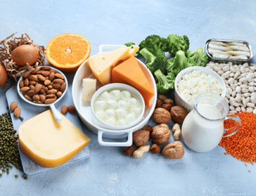 Calciumreiche Lebensmittel wie Käse, Gemüse und Nüsse auf blauem Tisch.