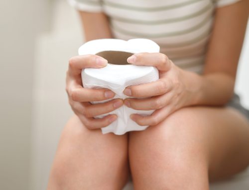 Frau auf der Toilette, drückt WC-Papier-Rolle fest, leidet an Hämorrhoiden